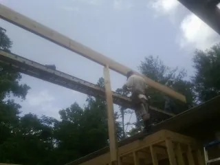 Carpenter setting a ridge beam over a new addition frame — Ice Dam Removal by Roofing Brothers in Olaton