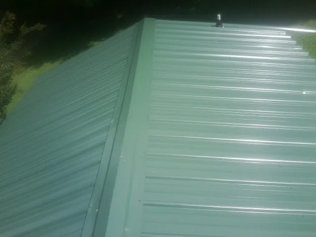 New green metal panels meeting at the ridge of a roof — Flat Roof Repair work by our crew in Olaton
