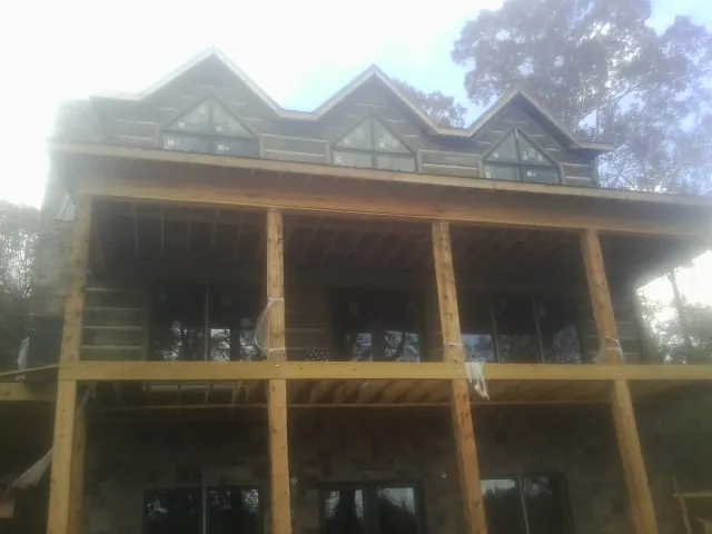 Dormers and porch framing on a large log home under construction — Roof Coating work by our crew in Olaton