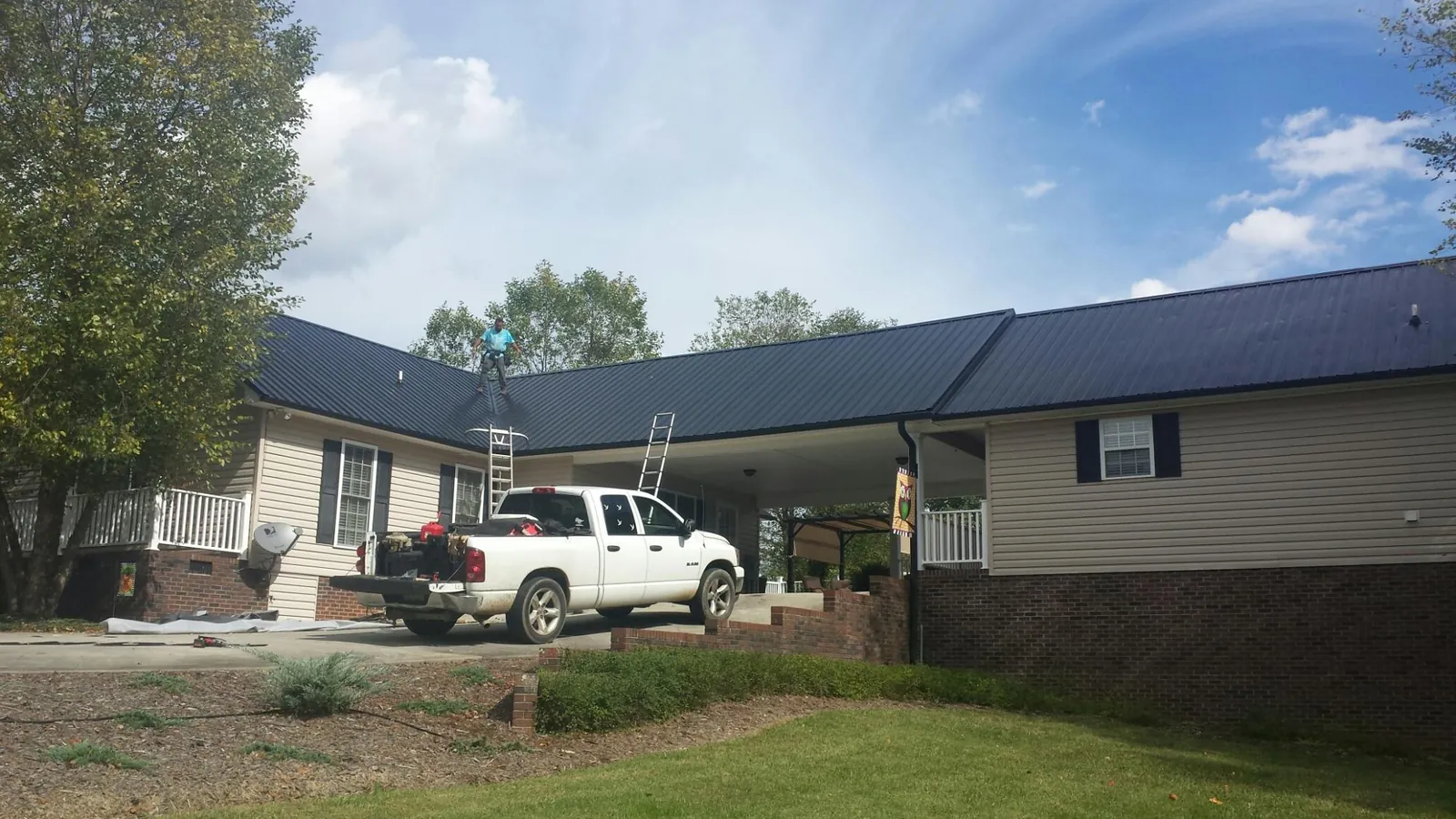 Black metal roof over a home and attached breezeway with ladders set in Olaton